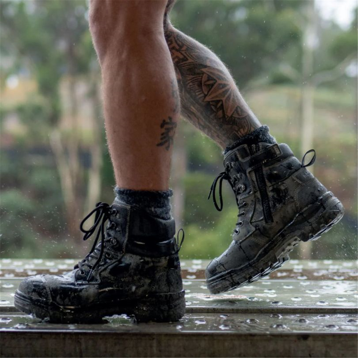 A tradie wearing black Blundstone 8071 Rotoflex safety boots while standing on scaffolding during wet weather